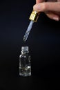 Luxurious facial serum container with dropper on black background