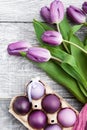 Luxurious fresh fashionable purple tulips on a wooden background next to Easter eggs Royalty Free Stock Photo