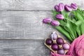 Luxurious fresh fashionable purple tulips on a wooden background next to Easter eggs Royalty Free Stock Photo