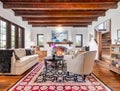 A luxurious, furnished living room with a lit fireplace and wood ceiling.