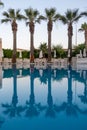 Luxurious hotel with swimming pool, palm trees, sun loungers Royalty Free Stock Photo