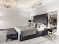 Luxurious large double bed in gray fabric with pillows and striped duvet with black bedside tables and black table lamps