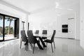 Luxurious modern dining room with white table, black chairs and white modern kitchen. Minimalistic style