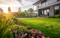 A luxurious modern home nestled in a lush, well-manicured landscape, bathed in the golden glow of the setting sun Royalty Free Stock Photo