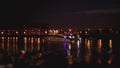 Luxurious modern private yacht and boat at the pier at night. Colorful lights of city glow shine reflected in water wave Royalty Free Stock Photo