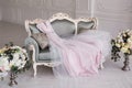 Luxurious pink wedding dress is lying on a grey sofa in a white room. Royalty Free Stock Photo