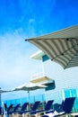 A luxurious resort provides rows of umbrellas and chairs for pampered guests to recline and relax under a deep blue sky