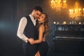 Luxurious sexy couple blonde woman dancing with handsome man slow dance in dark gothic room, holiday party. Guy hugs