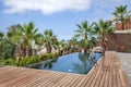 Luxurious swimming pool with clear blue water and surrounded by tropical palm trees and redwood decking, Abama Resort, Tenerife