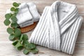 Luxurious white bathrobe and towel set with eucalyptus on wooden background Royalty Free Stock Photo