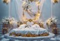 A luxurious white and gold bed is the centerpiece of the room, surrounded by white flowers and fairy lights. The bed has a gold