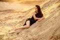 Luxurious young beautiful brunette woman in black shiny glamorous sequin dress posing in desert, yellow sand dunne Royalty Free Stock Photo