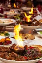Luxuriously decorated table with roast meat and fire in the middle of the plate Royalty Free Stock Photo