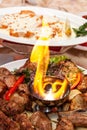 Luxuriously decorated table with roast meat and fire in the middle of the plate Royalty Free Stock Photo