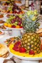 Luxuriously decorated table with tropical fruits, strawberries, bread and pineapple