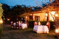 Luxury African Safari lodge outdoor dining on grass lawn with leather chairs and warm light from lamps