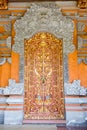 Balinese golden door, richly decorated with lions, birds, flowers and patterns, surrounded by concrete daemon and flowers Royalty Free Stock Photo