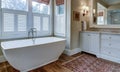 Luxury bathroom with large white tub, beautiful cabinets, and shiplap walls