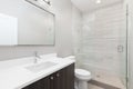 A modern bathroom with a wood cabinet and tiled shower. Royalty Free Stock Photo
