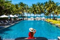 Luxury beach vacation in tropical beach hotel. Tourist woman in red dress relax near blue swimming pool in modern resort Royalty Free Stock Photo
