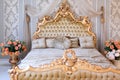 Luxury bedroom in light colors with golden furniture details. Big comfortable double royal bed in elegant classic Royalty Free Stock Photo