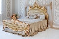 Luxury bedroom in light colors with golden furniture details. Big comfortable double royal bed in elegant classic Royalty Free Stock Photo