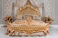 Luxury bedroom in light colors with golden furniture details. Big comfortable double royal bed in elegant classic Royalty Free Stock Photo