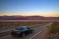 Luxury black fast American car driving on desert highway in Death Valley California, road trip, colourful sunrise mountains view Royalty Free Stock Photo