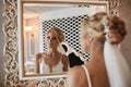 Luxury blonde model girl with platinum blonde curly hair looking at the mirror in vintage interior. Young blonde woman Royalty Free Stock Photo