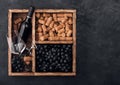 Luxury bottle of red wine and empty glass with dark grapes with corks and corkscrew inside vintage wooden box on black stone Royalty Free Stock Photo