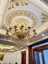 Elegant crystal chandelier hanging on the gilded gold ceiling. Luxury living room ceiling decoration