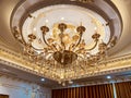 Elegant crystal chandelier hanging on the gilded gold ceiling. Luxury living room ceiling decoration