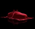 Luxury car prize covered with premium fabric on a black background. Red velvet cloth