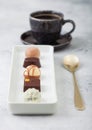 Luxury Chocolate candies in white porcelain plate with cup of black coffee and desset spoon on light table background Royalty Free Stock Photo