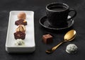 Luxury Chocolate candies in white porcelain plate with cup of black coffee and golden spoon on dark table background Royalty Free Stock Photo