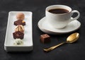 Luxury Chocolate candies in white porcelain plate with cup of black coffee and golden spoon on dark table background Royalty Free Stock Photo