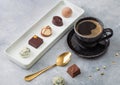 Luxury Chocolate candies in white porcelain plate with cup of black coffee and golden spoon on light table background Royalty Free Stock Photo