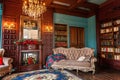 Luxury classic interior of home library. Sitting room with bookshelf, books, arm chair, sofa and fireplace Royalty Free Stock Photo