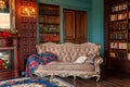 Luxury classic interior of home library. Sitting room with bookshelf, books, arm chair, sofa and fireplace Royalty Free Stock Photo