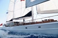 A luxury, classical, white color sailing yacht is sailing with full rigging and a man on the yacht.