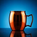 Luxury copper mug with handle on reflective surface against blue background Royalty Free Stock Photo