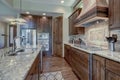 Luxury dark wood rich kitchen interior with copper stove hood and grey natural stone backsplash Royalty Free Stock Photo