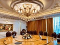 Luxury dining room interior with many shiny gold-plated details, crystal chandeliers, wooden chairs, and classic wall painting