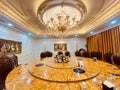 Luxury dining room interior with many shiny gold-plated details, crystal chandeliers, wooden chairs, and classic wall painting