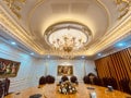 Luxury dining room interior with many shiny gold-plated details, crystal chandeliers, wooden chairs, and classic wall painting