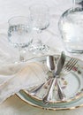 Elegant dinner set with silver knife, fork and spoon lying across luxyry porcelain dishes, and crystal glassware on cream vintage Royalty Free Stock Photo