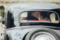 Happy stylish newlywed couple posing in retro car