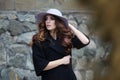 Luxury elegant woman in trendy black coat and hat standinf near