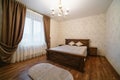 Luxury empty bedroom at home flat or hotel. Wooden floor walls. Lighting equipment hanging on ceiling. Bed with bedding blanket Royalty Free Stock Photo