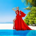 Luxury fashion. Elegant fashion model. Stylish female model in red long gown dress on the Maldives beach. Elegance. Classy woman Royalty Free Stock Photo